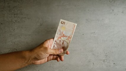 Man holding turkish lira in hand against a concrete background showing details of the currency