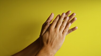 Hands clapping against a bright yellow background displaying an action concept of appreciation and...