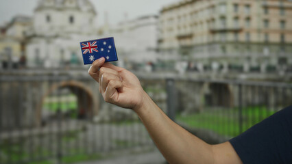 Man holding australian flag embroidery near roman ruins on a city street, highlighting travel and...