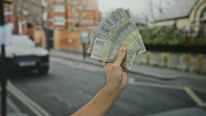 Man holding indonesian rupiah banknotes on a city street, showcasing currency in an outdoor urban...