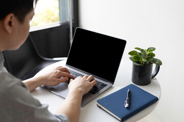 Man typing on laptop with blank screen for mockup. Hands on keyboard, a template for website, software or online business application display.