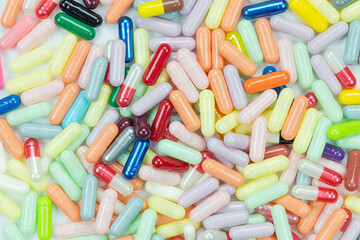 Top view of a large pile of colorful medicine capsules. Pharmaceutical industry, healthcare, and global drug manufacturing background concept.