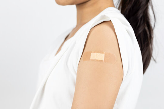 Vaccinated woman's arm with a bandage after injection. Concept of covid-19 immunization, flu shot, and public health vaccination campaign.