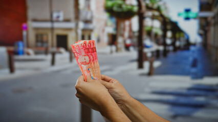 Hand holding philippine pesos on a city street, emphasizing business and investment opportunities...