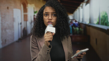 Woman reporter holding microphone on restaurant terrace indoors capturing street scene vibrant...