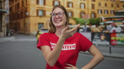 Woman smiles and gestures hand wearing volunteer shirt on city street; optimism solidarity...