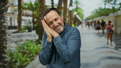 Mature man pretending to sleep in an urban park with a serene expression and relaxed posture on a...