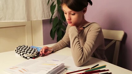 Fun cute surprise shocked emotion kid girl doing home exercises sitting at the table with book, copy books, pens, pencil case reading school book. Back to school. Concept education portrait video