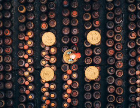 Aerial view of a person carrying items surrounded by rows of similar looking containers in a neatly organized pattern, Soy sauce maker, Ban Yen Nhan village, Hanoi Vietnam..