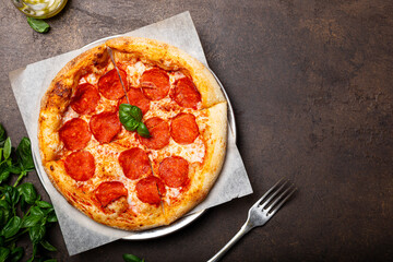 Homemade italian pizza with mozzarella, pepperoni sausages, on a dark background top view copy space for text