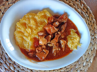 Top view of delicious lamb goulash on white plate with wicker place mat