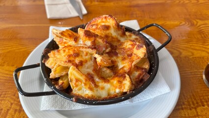 Hot Cheesy Potato Wedges Fresh from the Oven Served in a Rustic Pan on Wooden Table