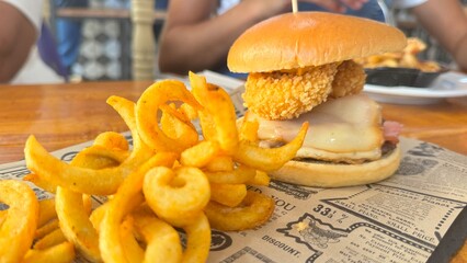 Delicious Gourmet Burger with Crispy Onion Ring and Curly Fries Served with a Cold Drink