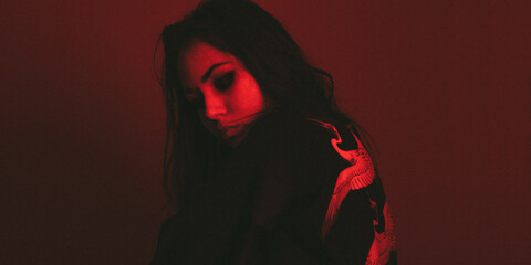 Moody portrait of a woman in colorful lighting, emotional expression in red, blue, and teal tones.
