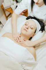 A girl cosmetologist massages the neck of a patient.