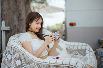 A woman is sitting on a white couch and taking a picture with a camera