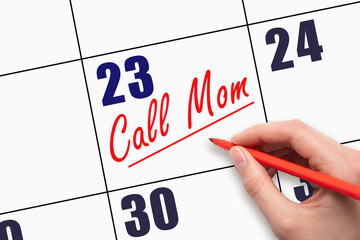 23rd day of the month.  Hand writing Call Mom reminder and drawing a line on calendar with red pen...