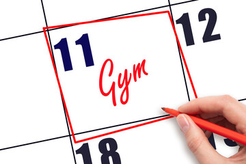 11th day of the month. Hand writing Gym reminder and drawing red frame on calendar with red pen on...