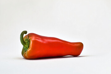 a red pepper with a green stem on a white surface
