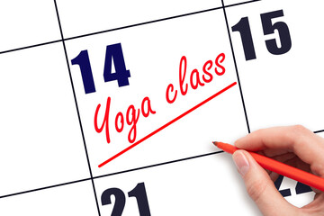 14th day of the month.  Hand writing Yoga class reminder and drawing a line on calendar with red...