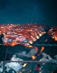 A rack of barbecue ribs cooking on a grill over an open flame. The ribs are glistening with sauce and appear to be nearly ready.
