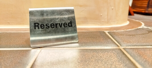 Reserved sign on silvery stainless steel, put on tiled table top in restaurant