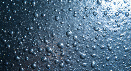Water Droplets on a Metallic Blue Surface Reflecting Light.