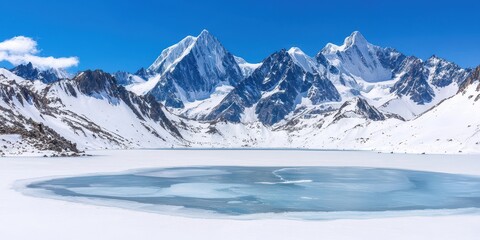 Obraz premium Vast snow covered mountain range under a clear blue sky with a partially frozen lake in the foreground