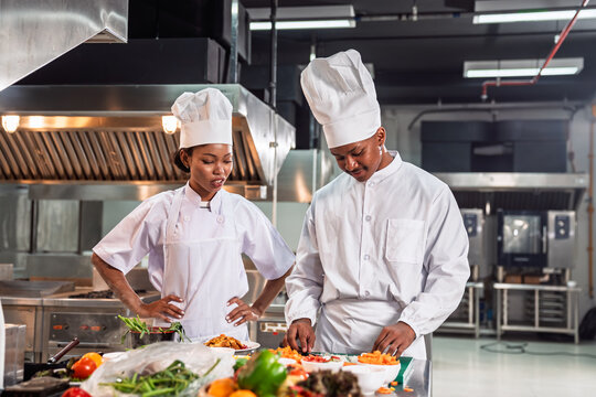 Chef Team of African American Man and Woman Preparing Food Together in Commercial Restaurant Kitchen with Confidence and Culinary Expertise