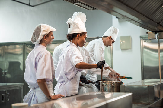 Cooking Class in Commercial Kitchen , Diverse Culinary Student Receives Hands-On Training from Head Chef, Learning with Passion and Focus