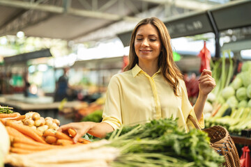 Cheerful woman selecting fresh vegetables in market, everything is fresh and organic. Smiling woman...
