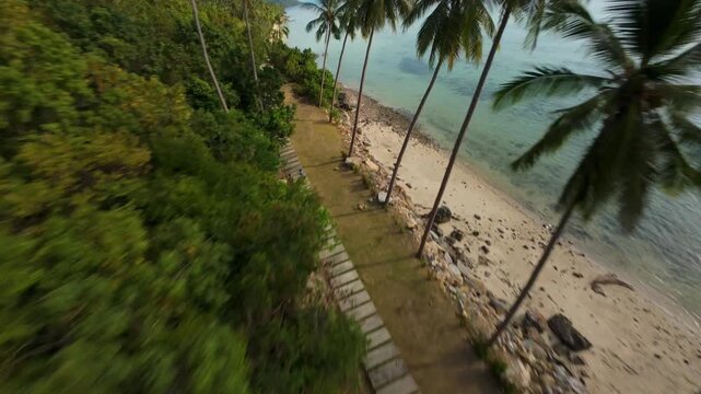 FPV Drone Swooping Over Green Cliff and Narrow Shoreline With Palm Trees by Crystal Sea, High Speed Curve, Jungle Coast Concept