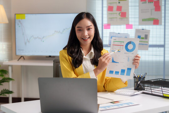 Asian businesswoman pointing at financial charts during video call