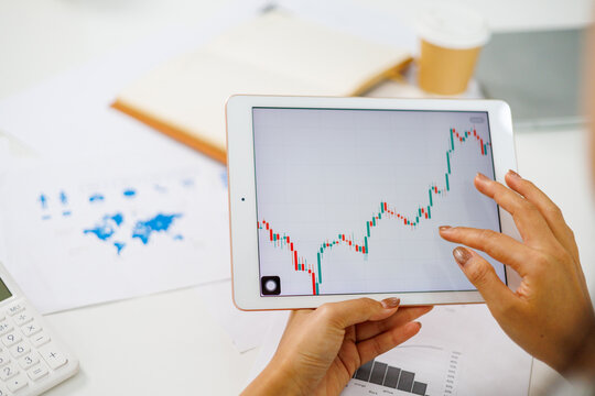 Businesswoman analyzing candlestick chart on tablet, evaluating financial market trends
