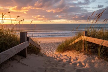A sandy path leads to the beach at sunset, framed by dunes and a wooden fence