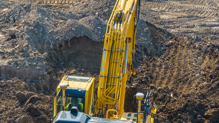 Aerial, overhead image of a excavator working on construction site moving dirt, earth.  Earthmoving, excavations, digging on soils	