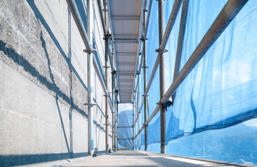 Scaffolding with scaffold netting. Low angle view of scaffolding platform with blue construction...