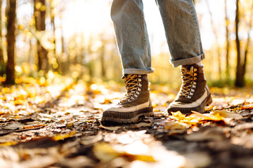 Close-up of female feet in boots standing on bright autumn leaves. A female tourist in hiking boots...