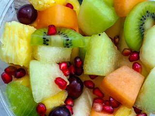 A bowl of fruit with a mix of kiwi, cantaloupe, and grapes