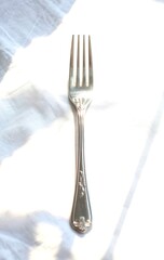 Elegant silver fork on white linen fabric