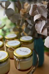 close up of a glass pots, personalized dessert pots, personalized dessert jars for christening, creamy pudding favors with ribbon, elegant baptism party sweets
