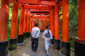 Japanese young couple walk along  big torii gate, Fushimi Inari, Kyoto