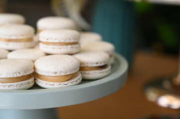 french macarons on a tray, elegant macarons dessert stand, white macarons with caramel filling, sweet party treat display
