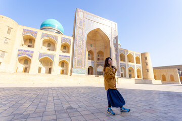 woman as a tourist have fun in front of Poi-Kalyan Kalyan mosque in bukhara Uzbekistan 