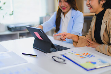 Businesswomen analyzing financial data on tablet with charts and graphs in office meeting