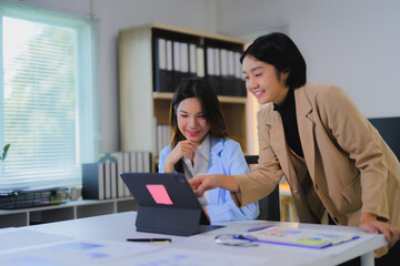 Obraz premium Asian businesswomen discussing and working together using tablet in office