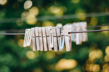Close-up of wooden clothespins hanging on a wire against a blurred green natural background with...