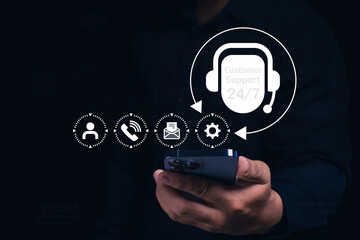A person holds a smartphone with virtual icons showing 24/7 customer support, communication, and...