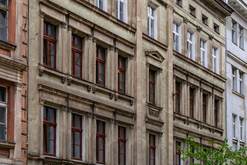 Fototapeta premium Historic tenement house in Poznań with decorative facade and red window frames, 19th-century urban architecture.