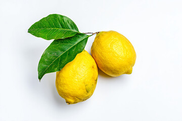 two lemons with leaves on a white surface